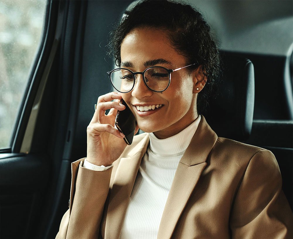 Woman smiling and talking on the phone in a car
